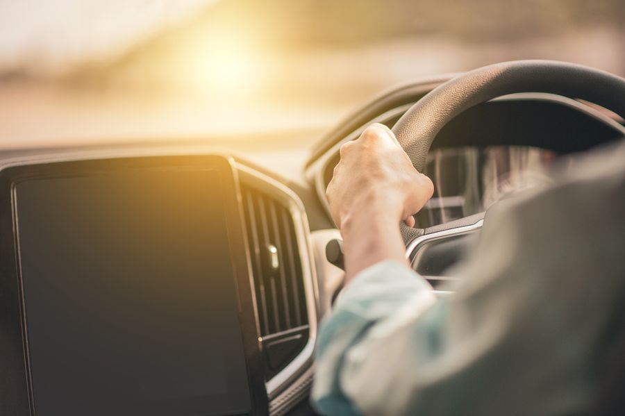 Hands on a steering wheel in the sun