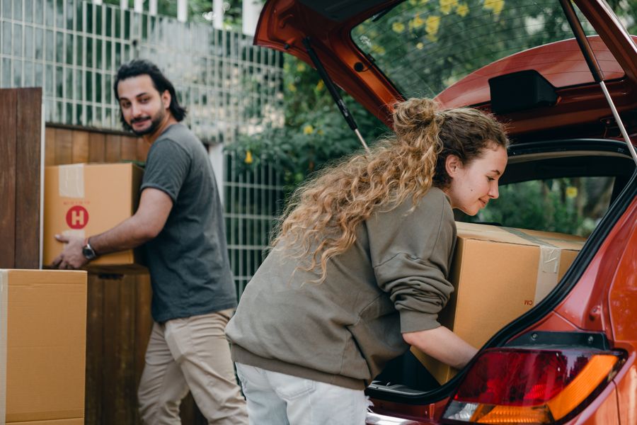 A couple unloading moving boxes from a car